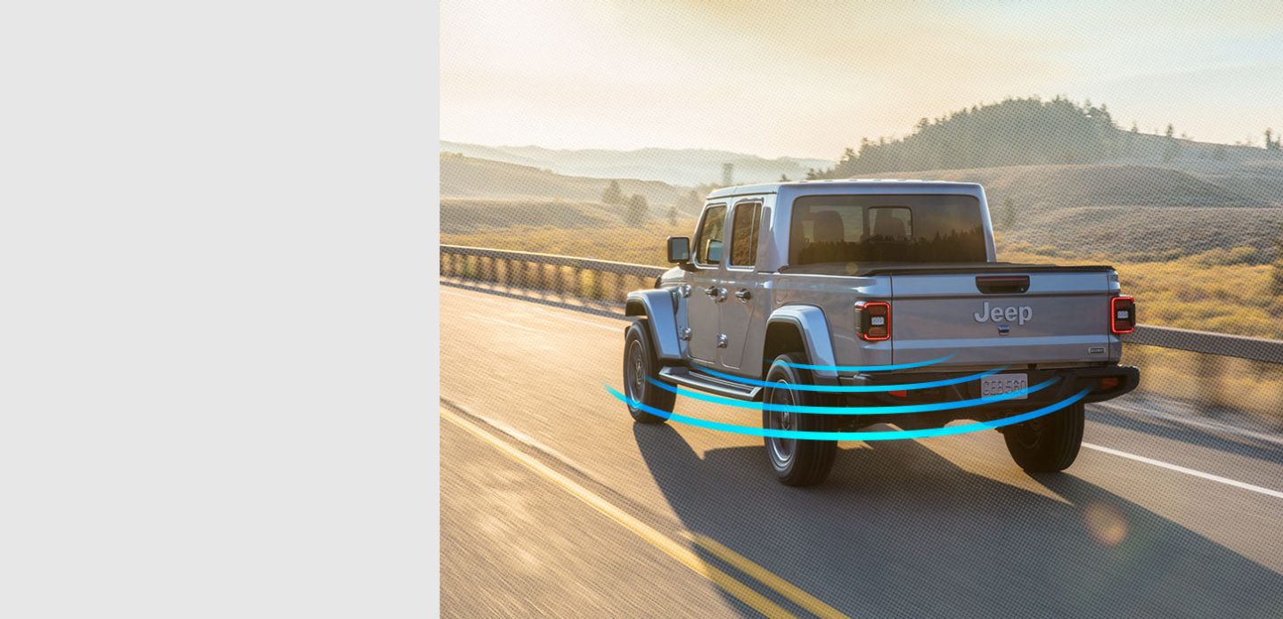 Grey Gladiator driving down road with blind spot monitoring on