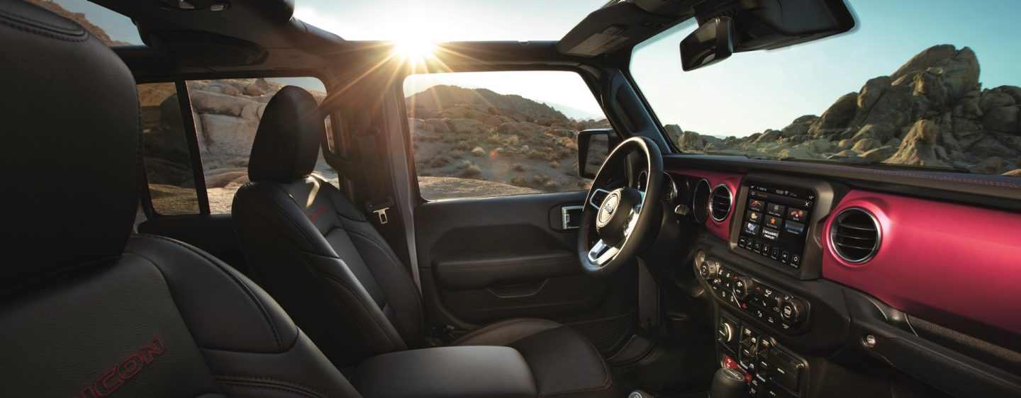 The interior of the 2023 Jeep Gladiator Overland with its top off, focusing on the front seats and dash.