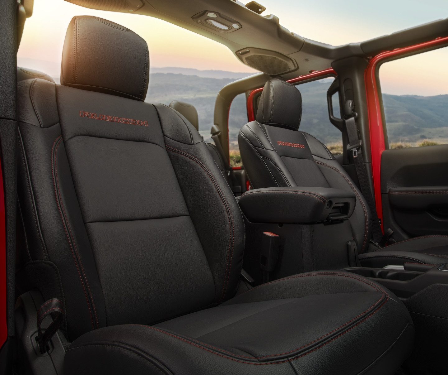 The interior of the 2023 Jeep Gladiator Mojave with its top off, focusing on the ocean and sky visible through the windshield, open roof and open window.