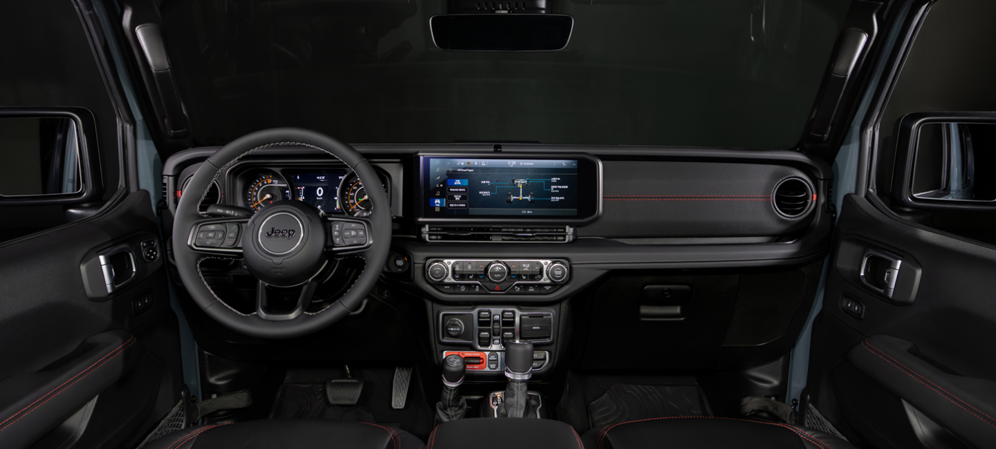 A gray 2025 Jeep Gladiator Mojave X kicking up sand as it is driven across a desert plain.